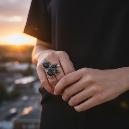 hand model wearing Desert Rocker adjustable antique brass ring with black and red stones