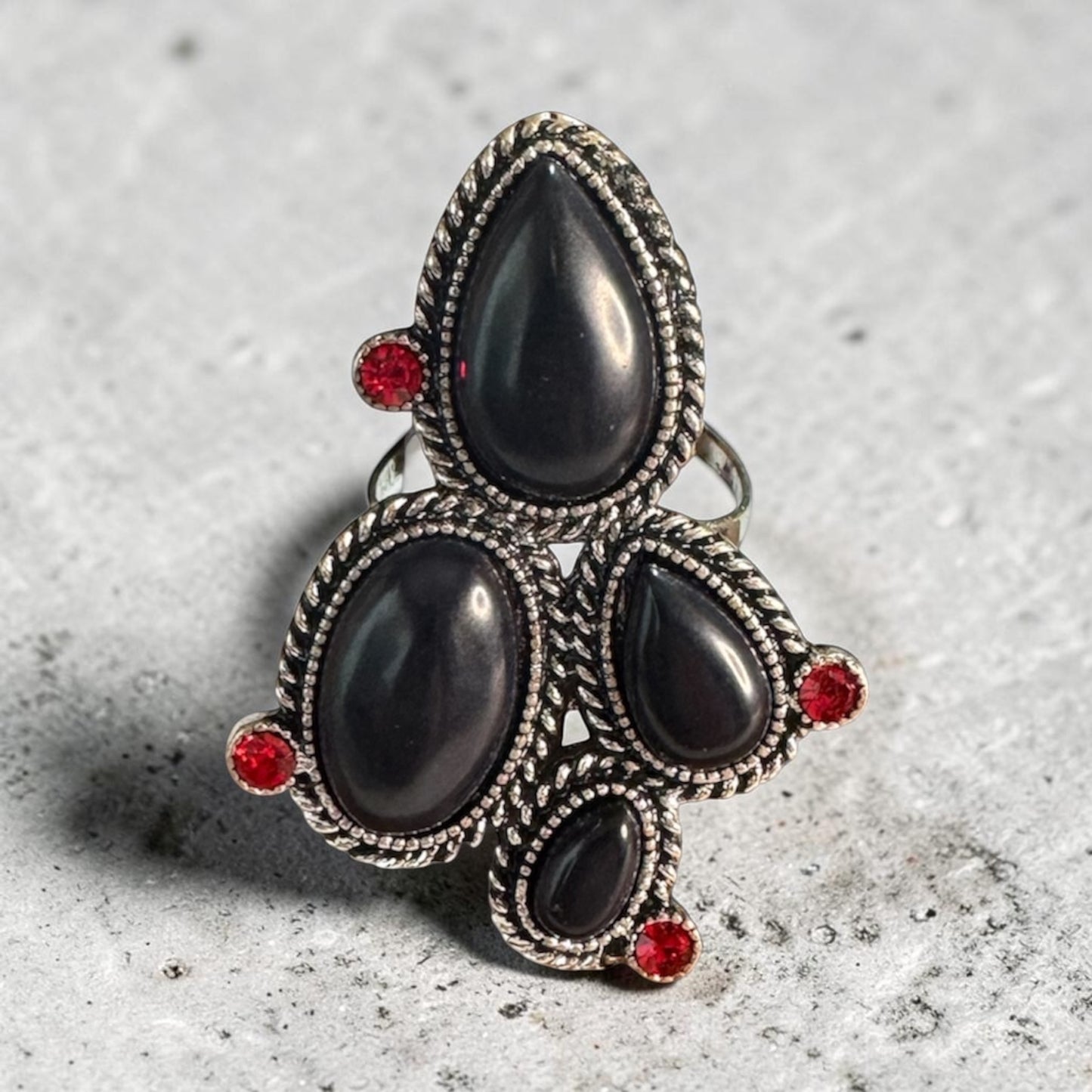 Desert Rocker adjustable antique brass ring with black and red stones ON stone counter