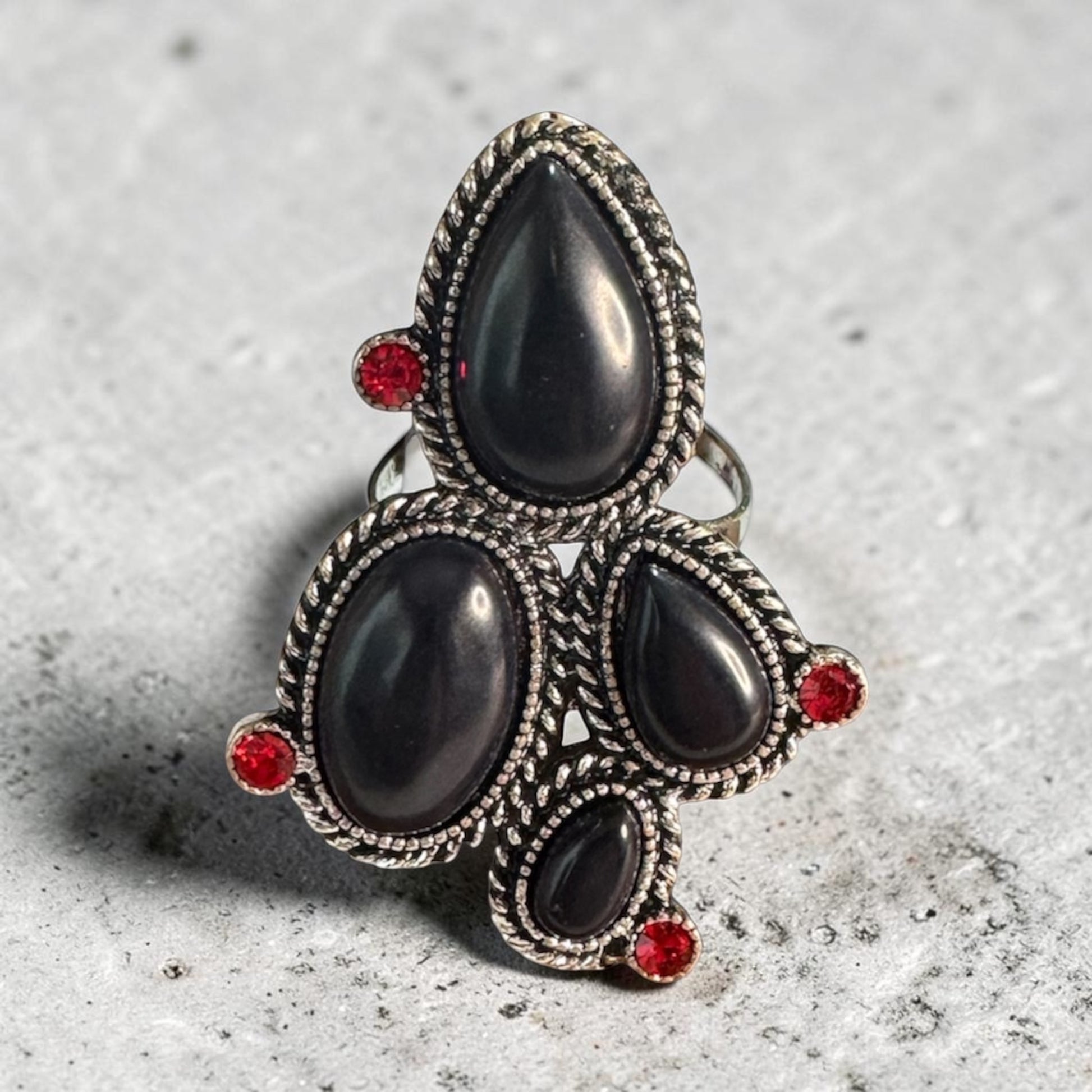 Desert Rocker adjustable antique brass ring with black and red stones ON stone counter