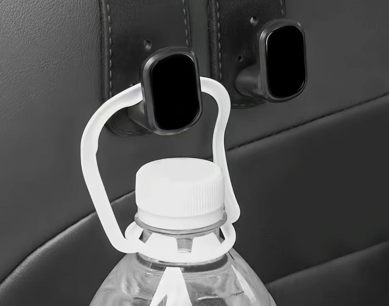 The Purse Perch™ organizing groceries and shopping bags behind a vehicle seat. holding the white cap of a clear plastic water bottle.