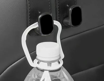 The Purse Perch™ organizing groceries and shopping bags behind a vehicle seat. holding the white cap of a clear plastic water bottle.
