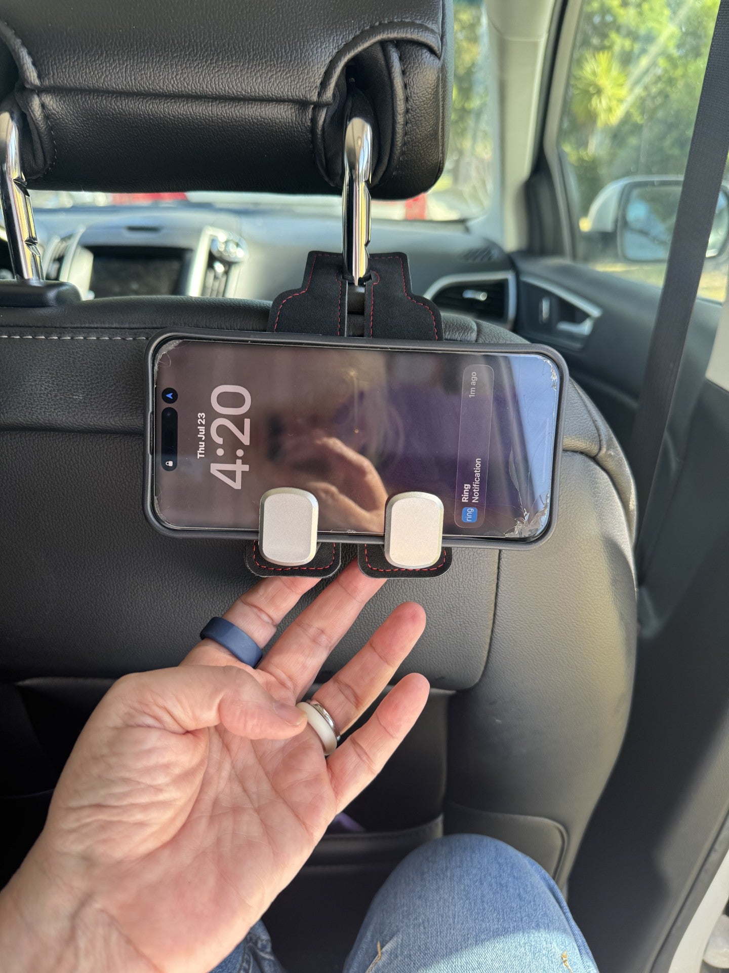 Black Suede The Purse Perch™ luxury car organizer holding a phone for back seat passenger viewing. 